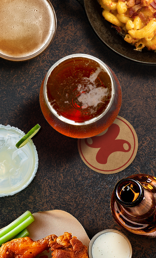 Drinks on table alongside mac and cheese and chicken wings at Mac + Cheese Kitchen
